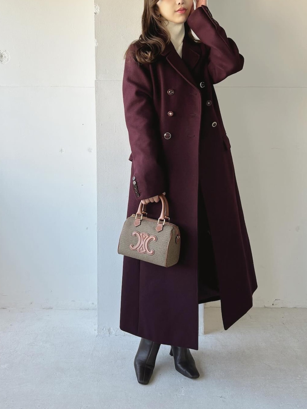 レッド系のチェスターコート、ブラウン系のブーツ、ホワイト系のニット/セーターを着用したレディースの冬コーディネートの2枚目の写真