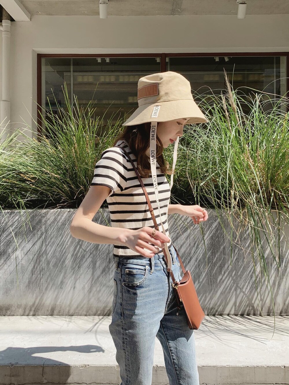 ブルー系のデニムパンツ、ブラック系のTシャツ/カットソー、ブラウン系のショルダーバッグを着用したレディースの春コーディネートの5枚目の写真