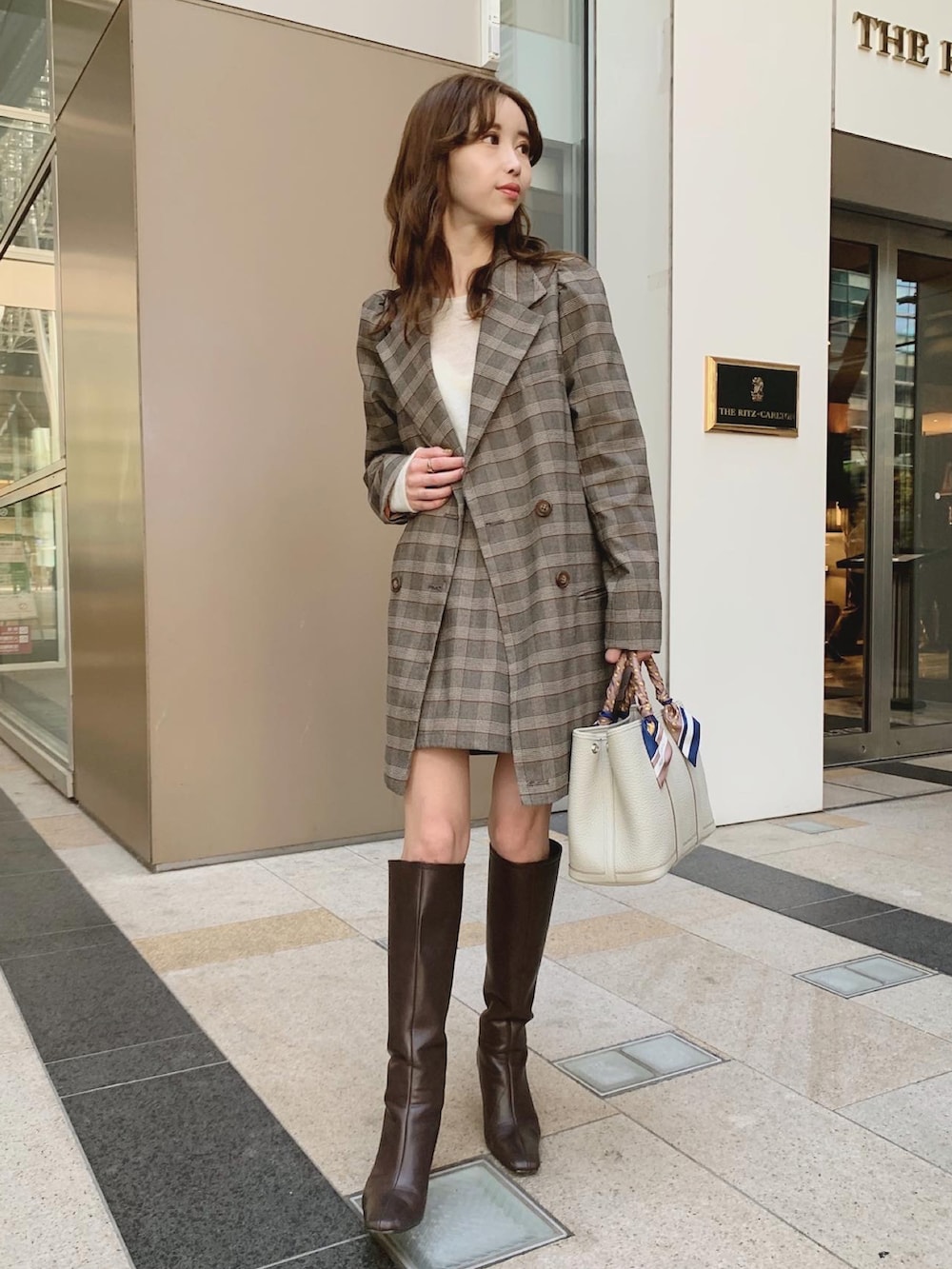 ブラウン系のテーラードジャケット、ブラウン系のブーツ、ホワイト系のニット/セーターを着用したレディースの秋コーディネートの2枚目の写真