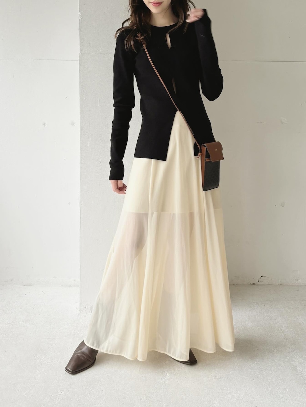 ブラック系のニット/セーター、ホワイト系のスカート、ブラウン系のバッグを着用したレディースの春コーディネートの2枚目の写真
