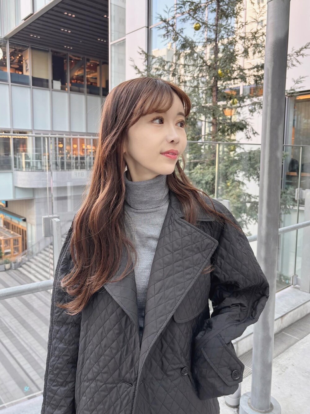 ブラック系のトレンチコート、グレー系のニット/セーター、ブラック系のブーツを着用したレディースの冬コーディネートの3枚目の写真