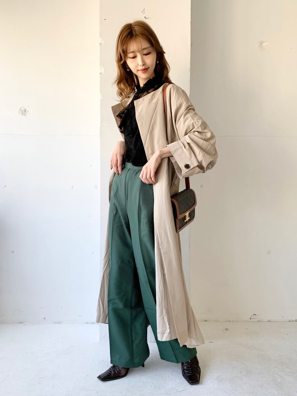 ベージュ系のノーカラーコート、ブラック系のシャツ/ブラウス、ブラウン系のバッグを着用したレディースの春コーディネートの2枚目の写真