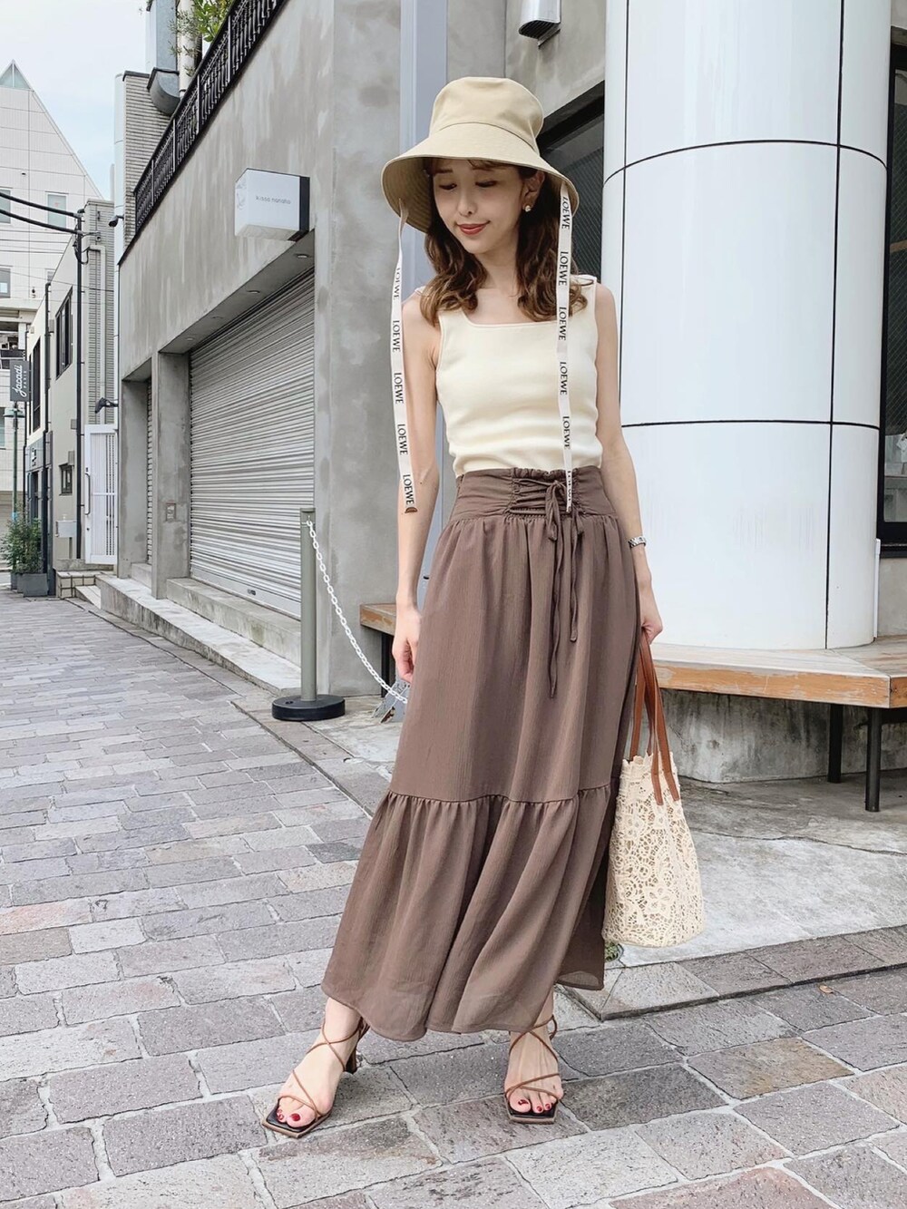 ブラウン系のスカート、ブラウン系のサンダル、ベージュ系のタンクトップを着用したレディースの夏コーディネートの2枚目の写真