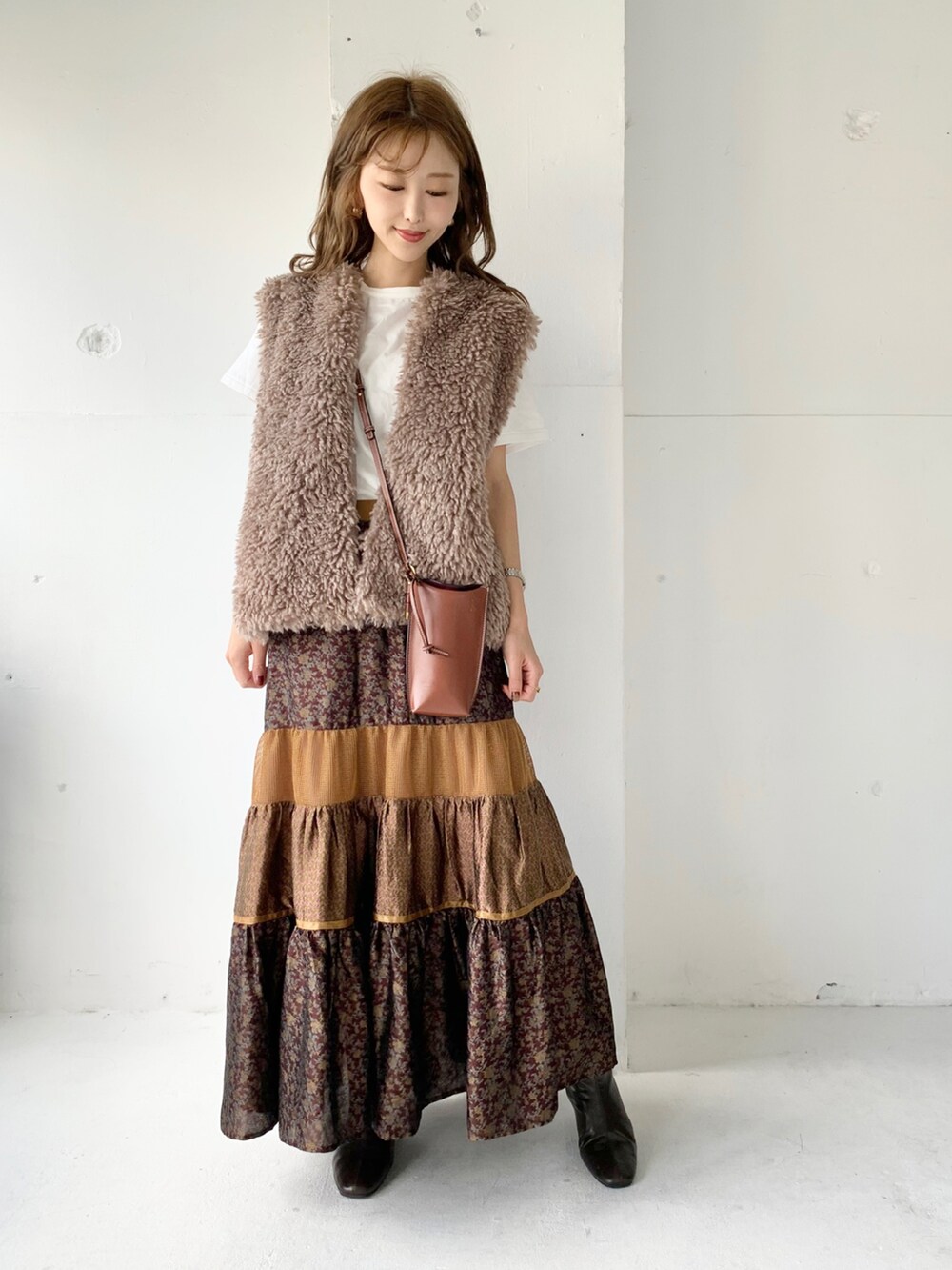 ブラウン系のベスト、ブラウン系のスカート、ホワイト系のTシャツ/カットソーを着用したレディースの秋コーディネートの2枚目の写真