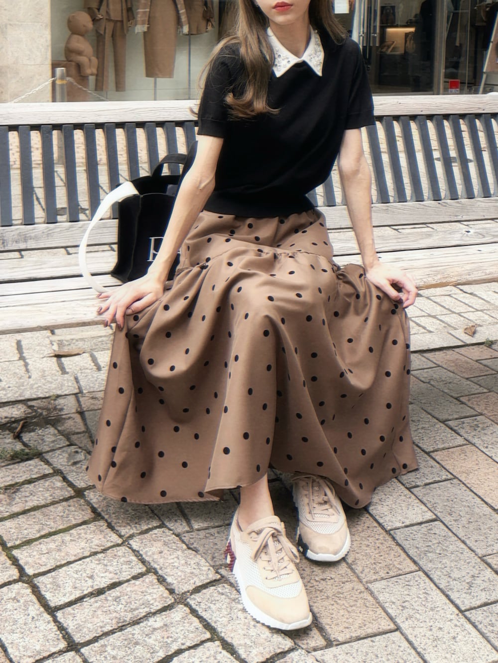 ブラウン系のニット/セーター、ブラウン系のスカート、ブラック系のバッグを着用したレディースの秋コーディネートの2枚目の写真