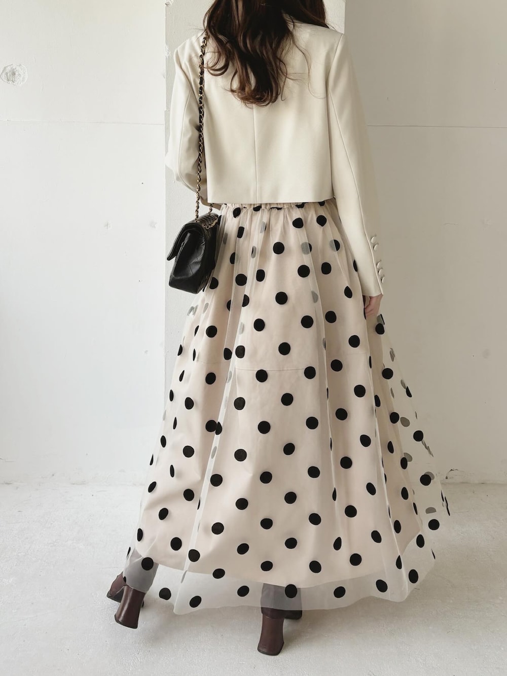 ベージュ系のノーカラージャケット、ベージュ系のスカート、ブラウン系のブーツを着用したレディースの春コーディネートの4枚目の写真