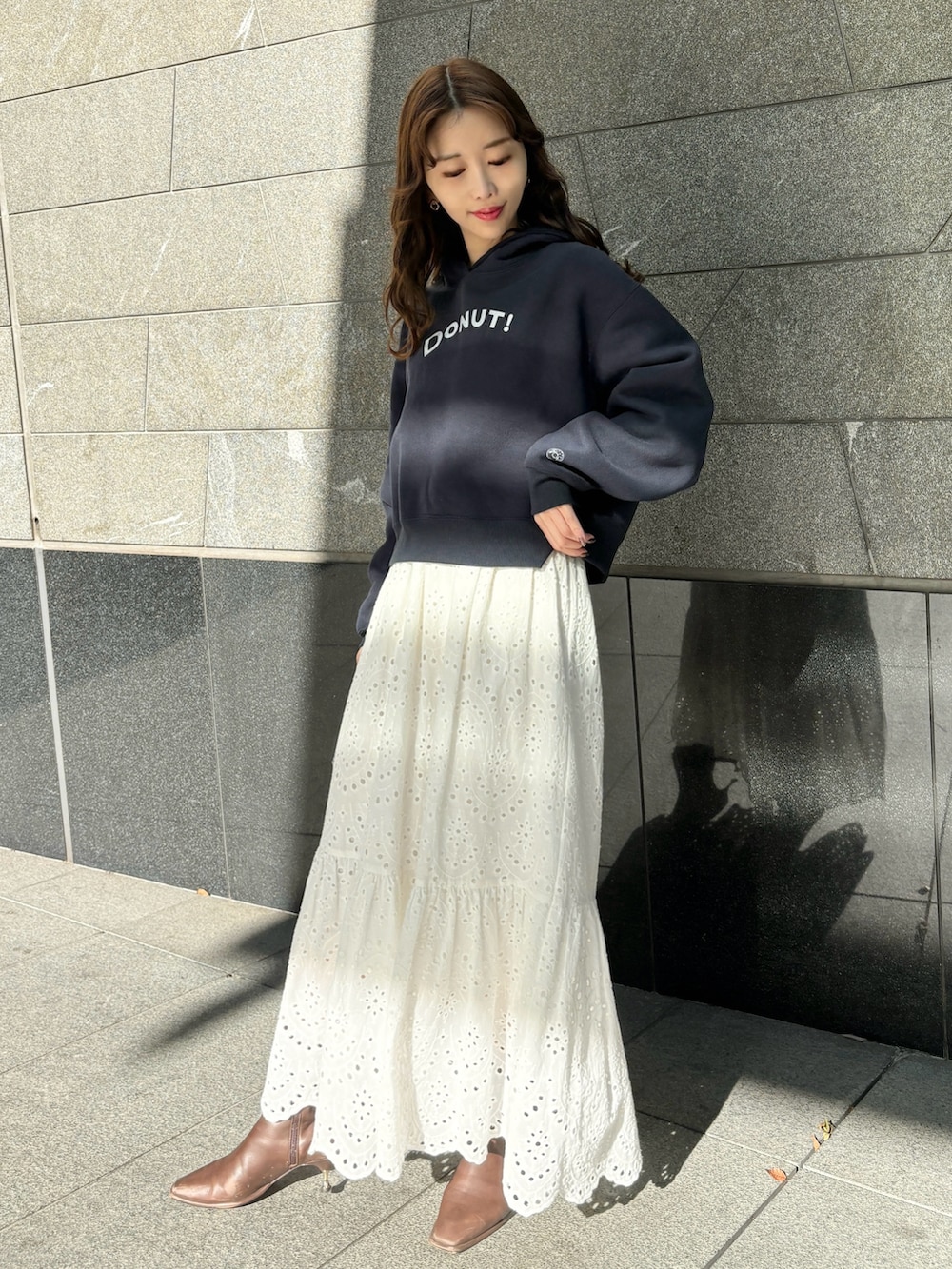 ブルー系のパーカー、ホワイト系のスカート、ブラウン系のブーツを着用したレディースの冬コーディネートの2枚目の写真