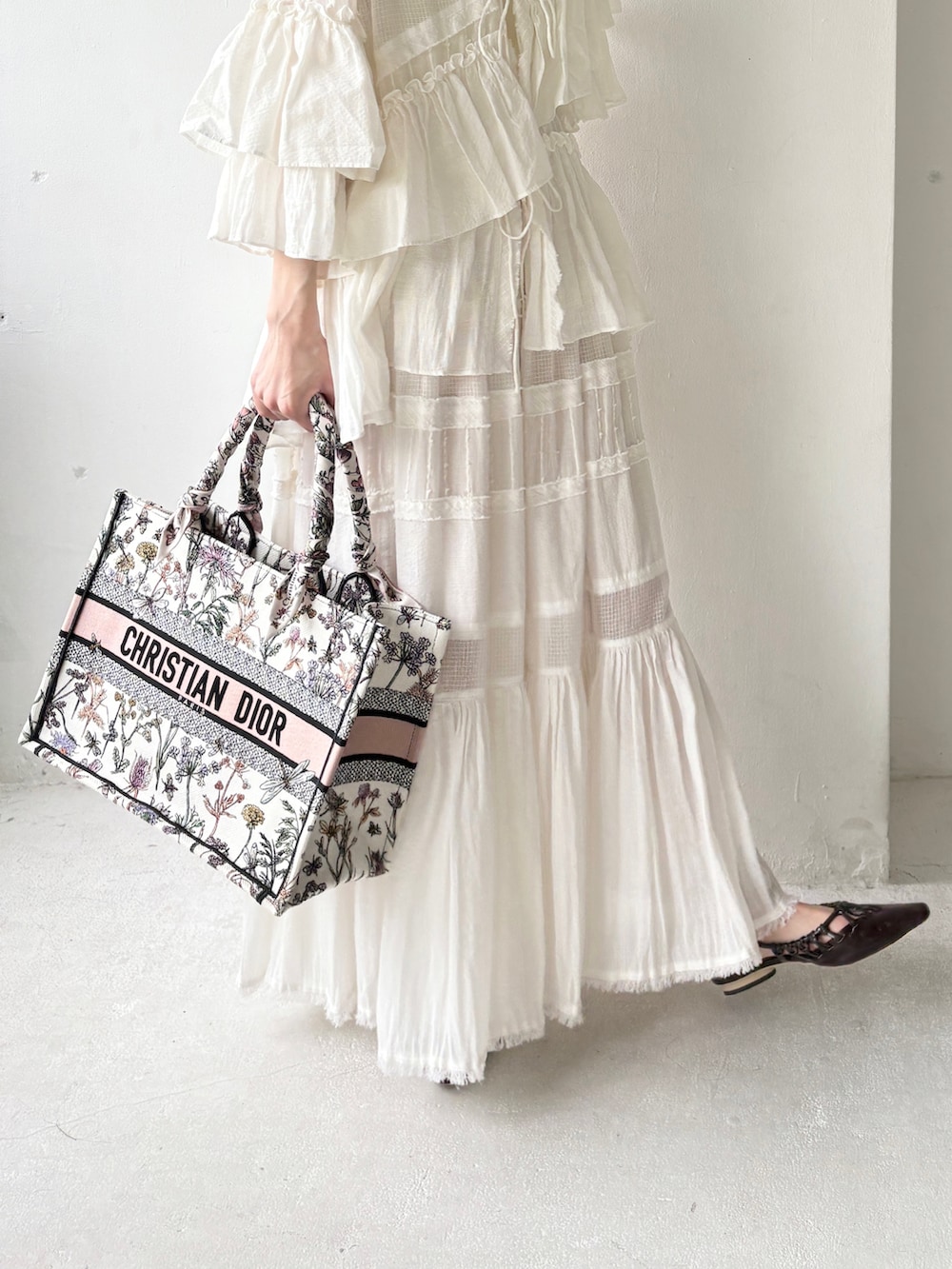 ホワイト系のシャツ/ブラウス、ホワイト系のスカート、ブラウン系のサンダルを着用したレディースの夏コーディネートの3枚目の写真