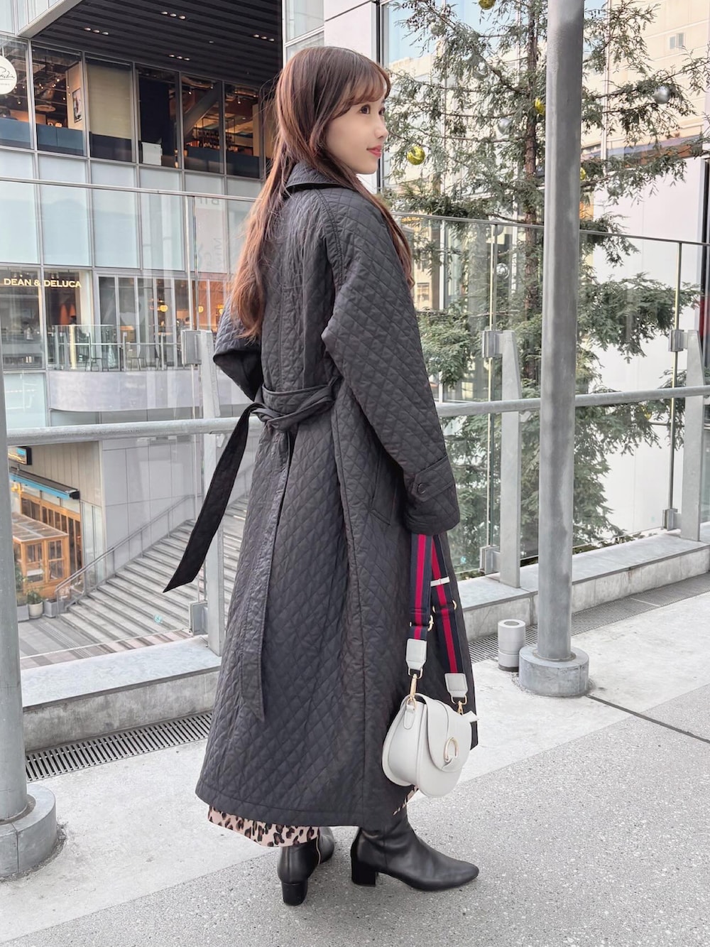 ブラック系のトレンチコート、グレー系のニット/セーター、ブラック系のブーツを着用したレディースの冬コーディネートの2枚目の写真