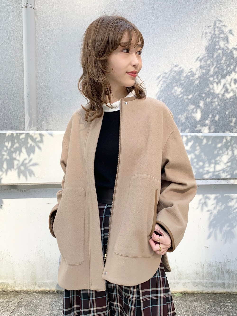 ベージュ系のブルゾン、ブラック系のニット/セーター、レッド系のスカートを着用したレディースの秋コーディネートの3枚目の写真