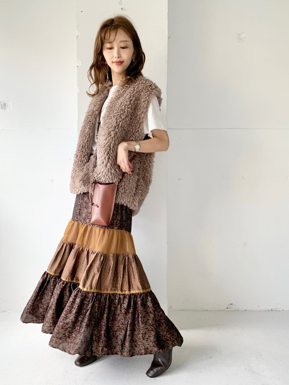 ブラウン系のベスト、ブラウン系のスカート、ホワイト系のTシャツ/カットソーを着用したレディースの秋コーディネートの3枚目の写真