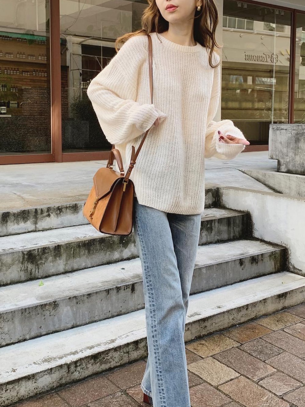 ホワイト系のニット/セーター、ブルー系のデニムパンツ、ブラウン系のパンプスを着用したレディースの秋コーディネートの2枚目の写真