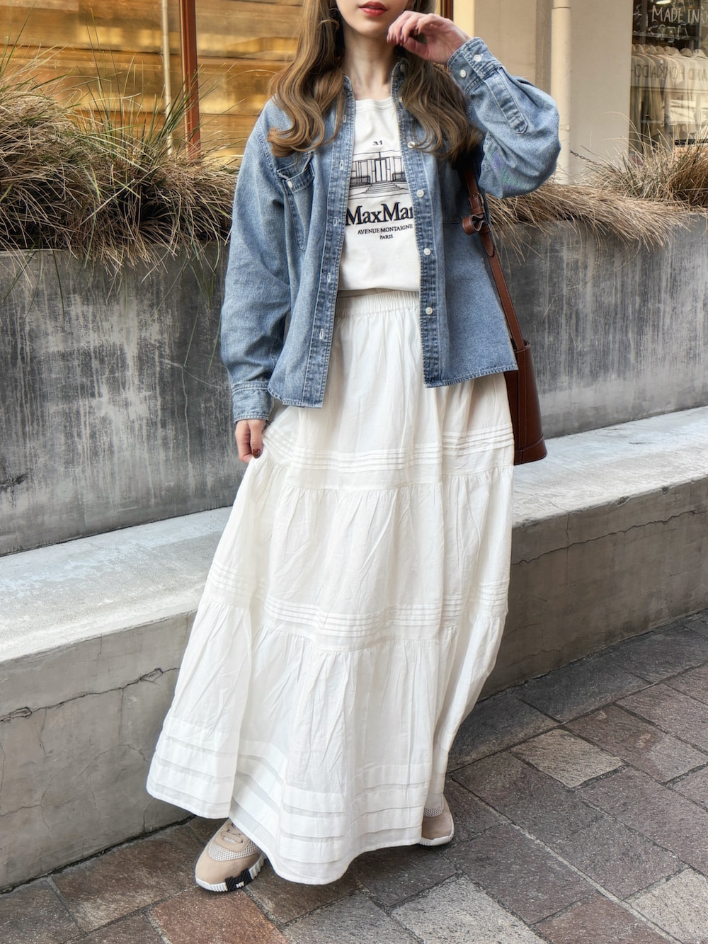 ブルー系のシャツ/ブラウス、ホワイト系のスカート、ベージュ系のTシャツ/カットソーを着用したレディースの春コーディネートの2枚目の写真