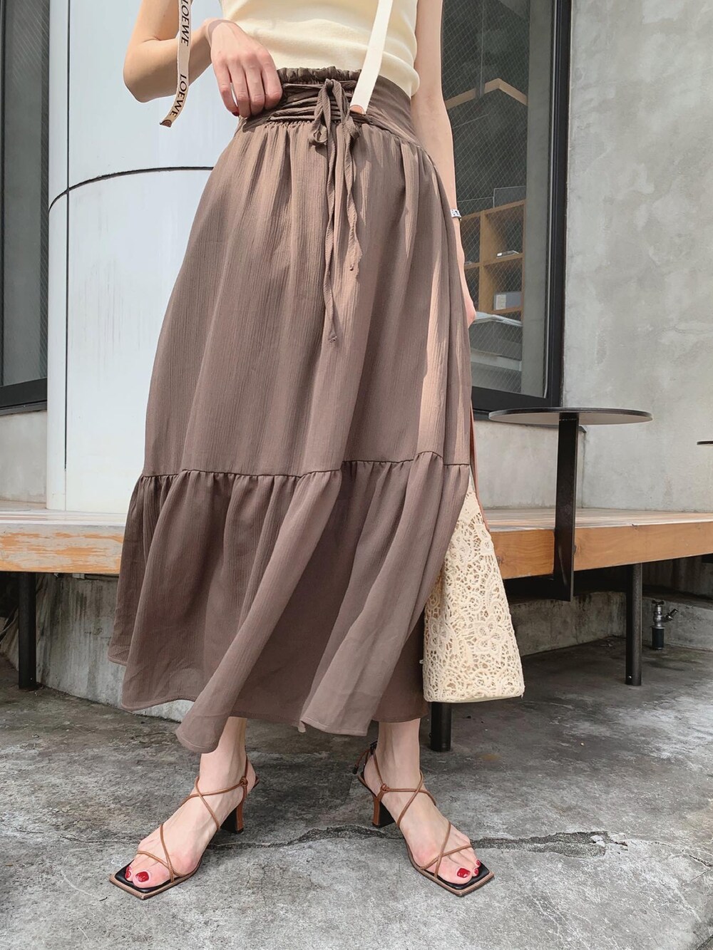 ブラウン系のスカート、ブラウン系のサンダル、ベージュ系のタンクトップを着用したレディースの夏コーディネートの3枚目の写真