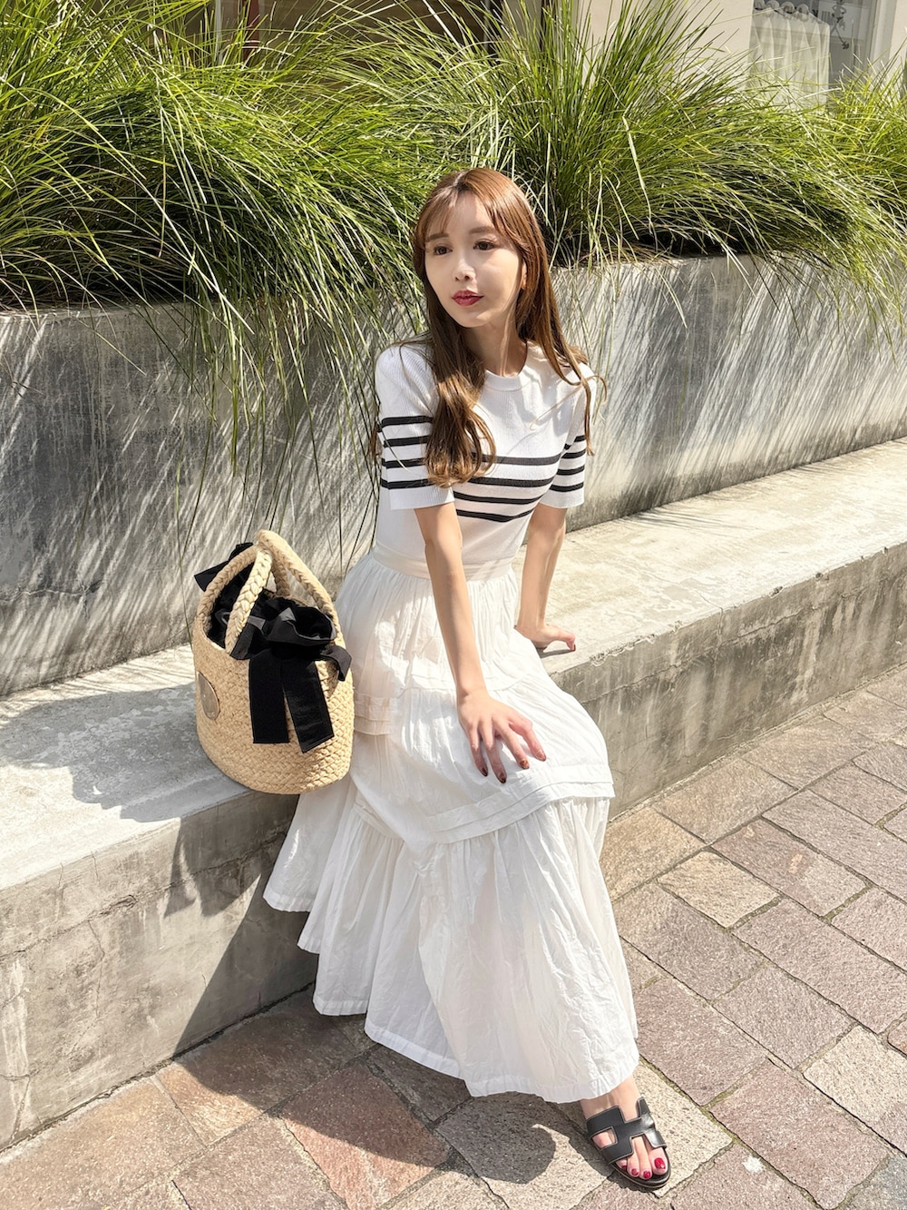 ホワイト系のワンピース、ブラック系のサンダル、ベージュ系のかごバッグを着用したレディースの夏コーディネートの2枚目の写真