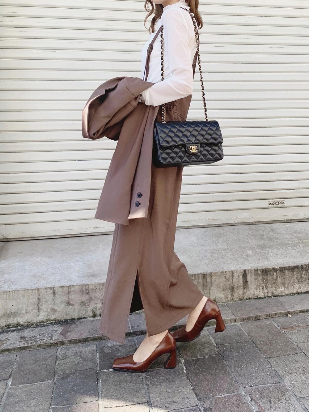 ブラウン系のテーラードジャケット、ブラウン系のスカート、ホワイト系のTシャツ/カットソーを着用したレディースの秋コーディネートの3枚目の写真