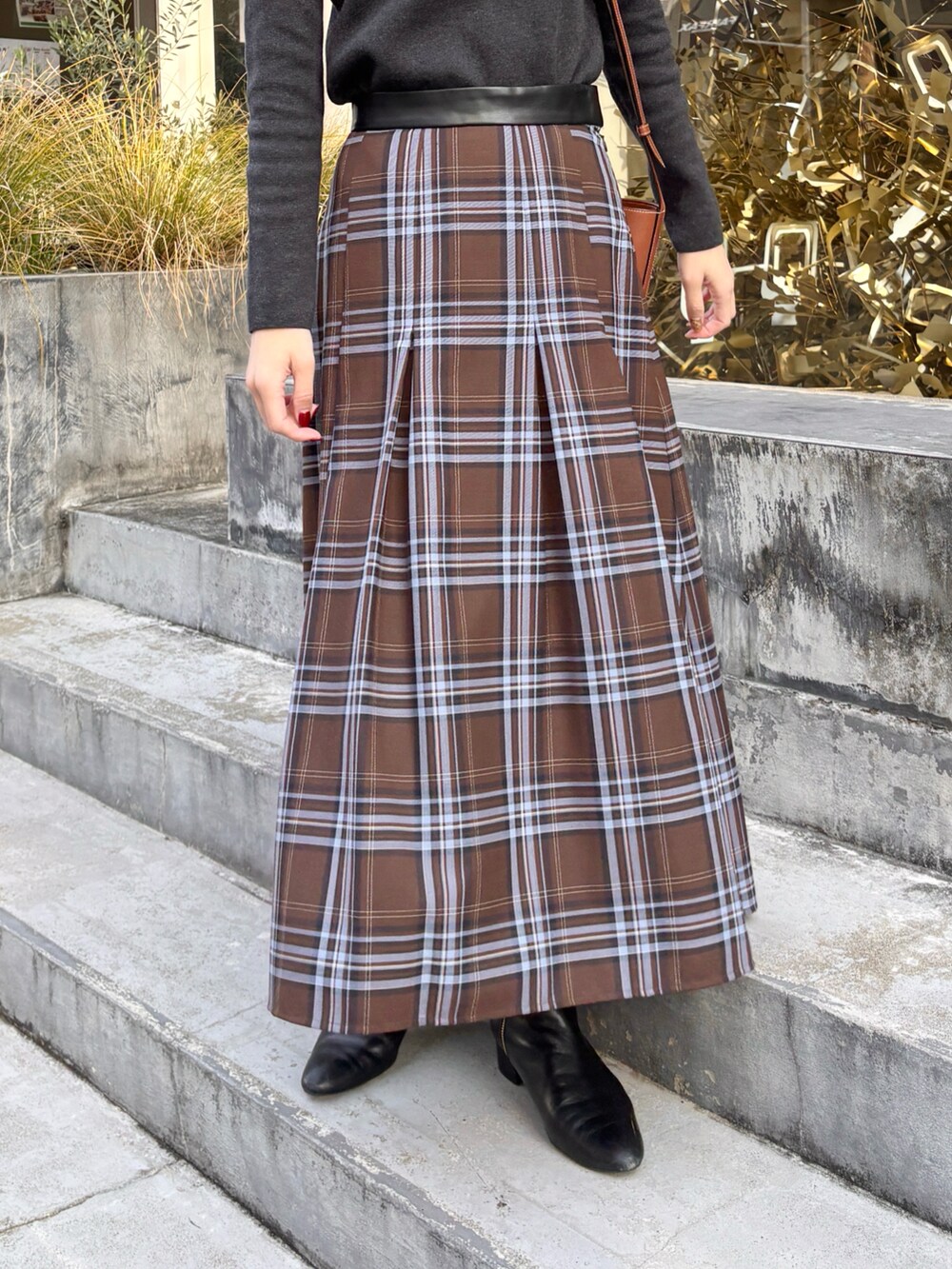 ブラウン系のスカート、グレー系のニット/セーター、ブラック系のブーツを着用したレディースの冬コーディネートの2枚目の写真