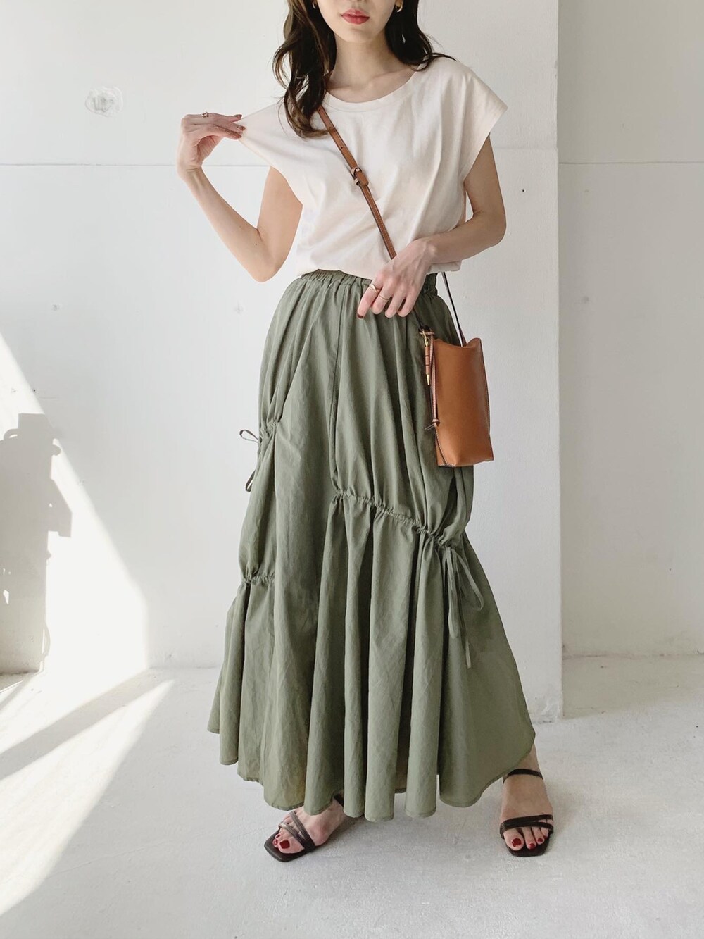 グリーン系のスカート、ブラウン系のサンダル、ホワイト系のTシャツ/カットソーを着用したレディースの夏コーディネートの2枚目の写真