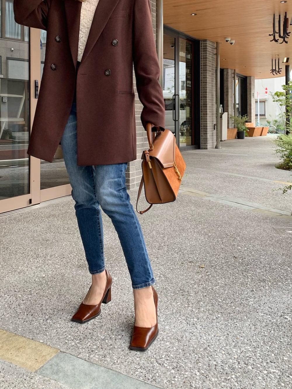 ブラウン系のテーラードジャケット、ホワイト系のTシャツ/カットソー、ブルー系のデニムパンツを着用したレディースの秋コーディネートの3枚目の写真