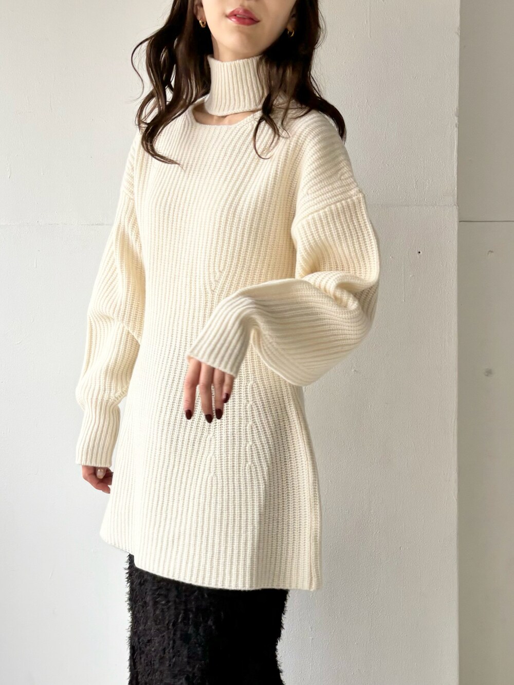 ホワイト系のニット/セーター、ブラウン系のブーツ、ブラック系のスカートを着用したレディースの冬コーディネートの2枚目の写真