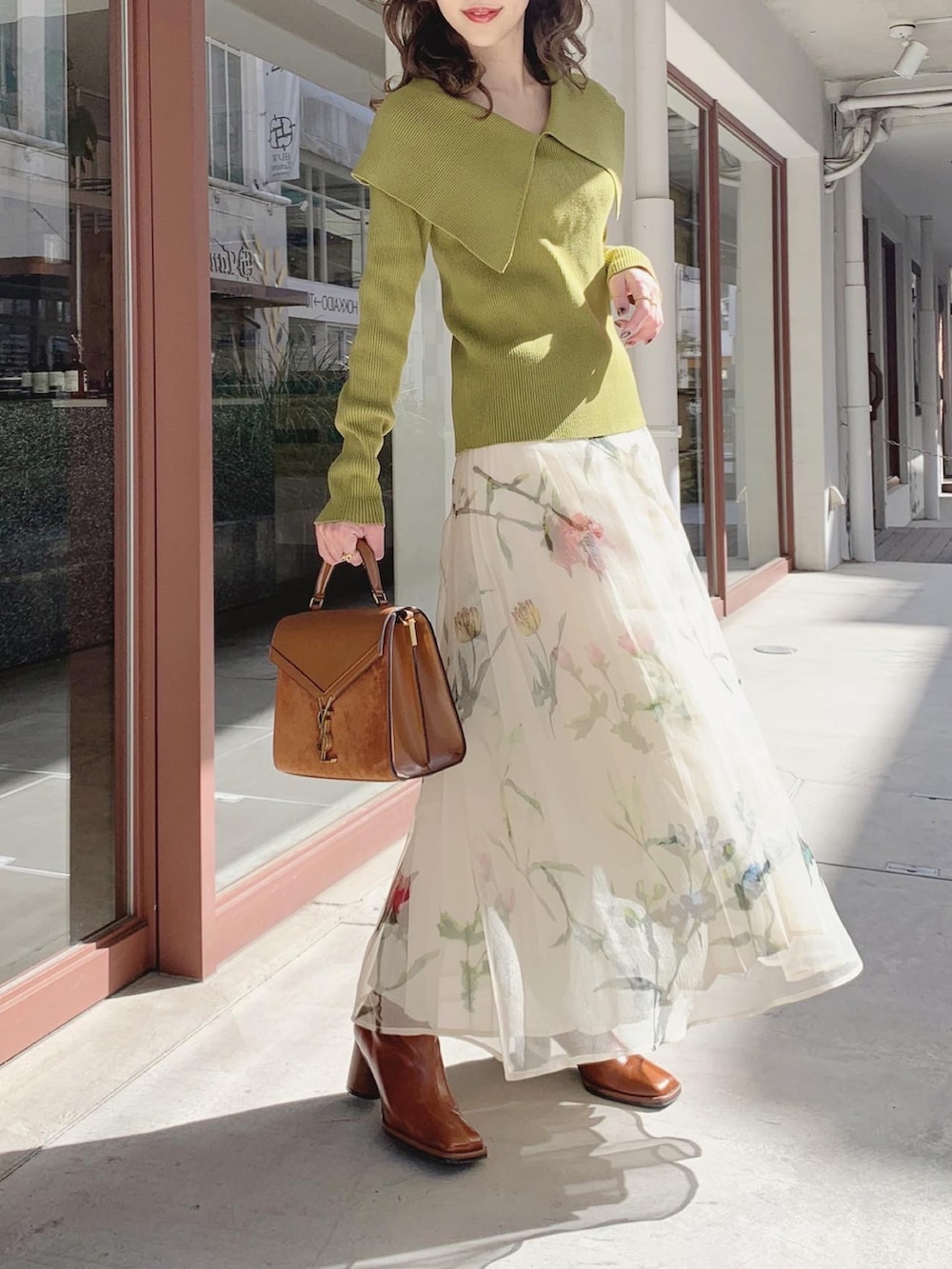 グリーン系のニット/セーター、ホワイト系のスカート、ブラウン系のブーツを着用したレディースの春コーディネートの2枚目の写真