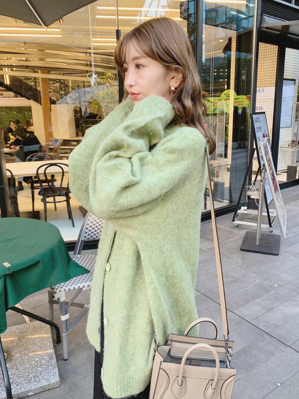 グリーン系のカーディガン/ボレロ、ブラック系のスカート、レッド系のブーツを着用したレディースの冬コーディネートの2枚目の写真