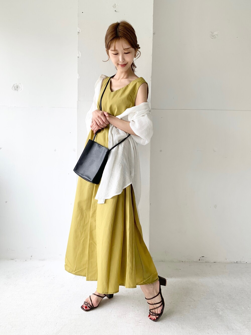 イエロー系のワンピース、ホワイト系のシャツ/ブラウス、ブラウン系のサンダルを着用したレディースの夏コーディネートの2枚目の写真