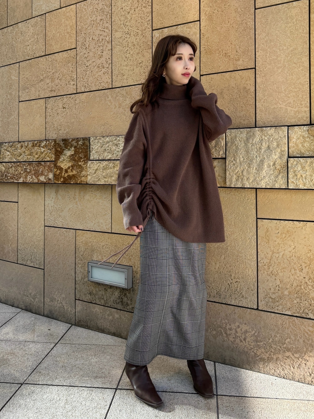ブラウン系のニット/セーター、ブラック系のスカート、ブラウン系のブーツを着用したレディースの冬コーディネートの3枚目の写真