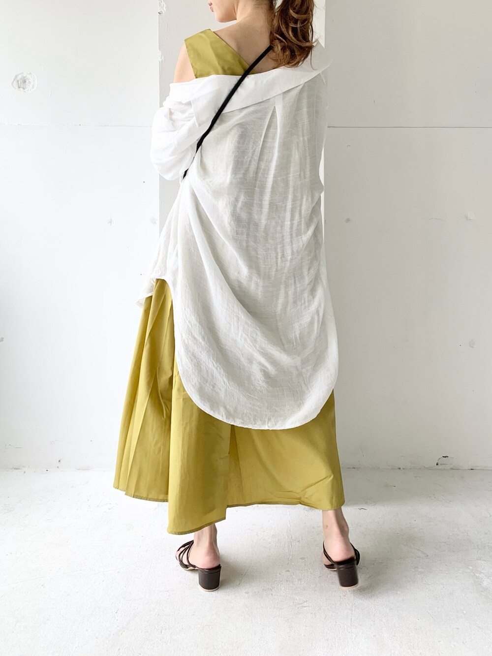 イエロー系のワンピース、ホワイト系のシャツ/ブラウス、ブラウン系のサンダルを着用したレディースの夏コーディネートの4枚目の写真