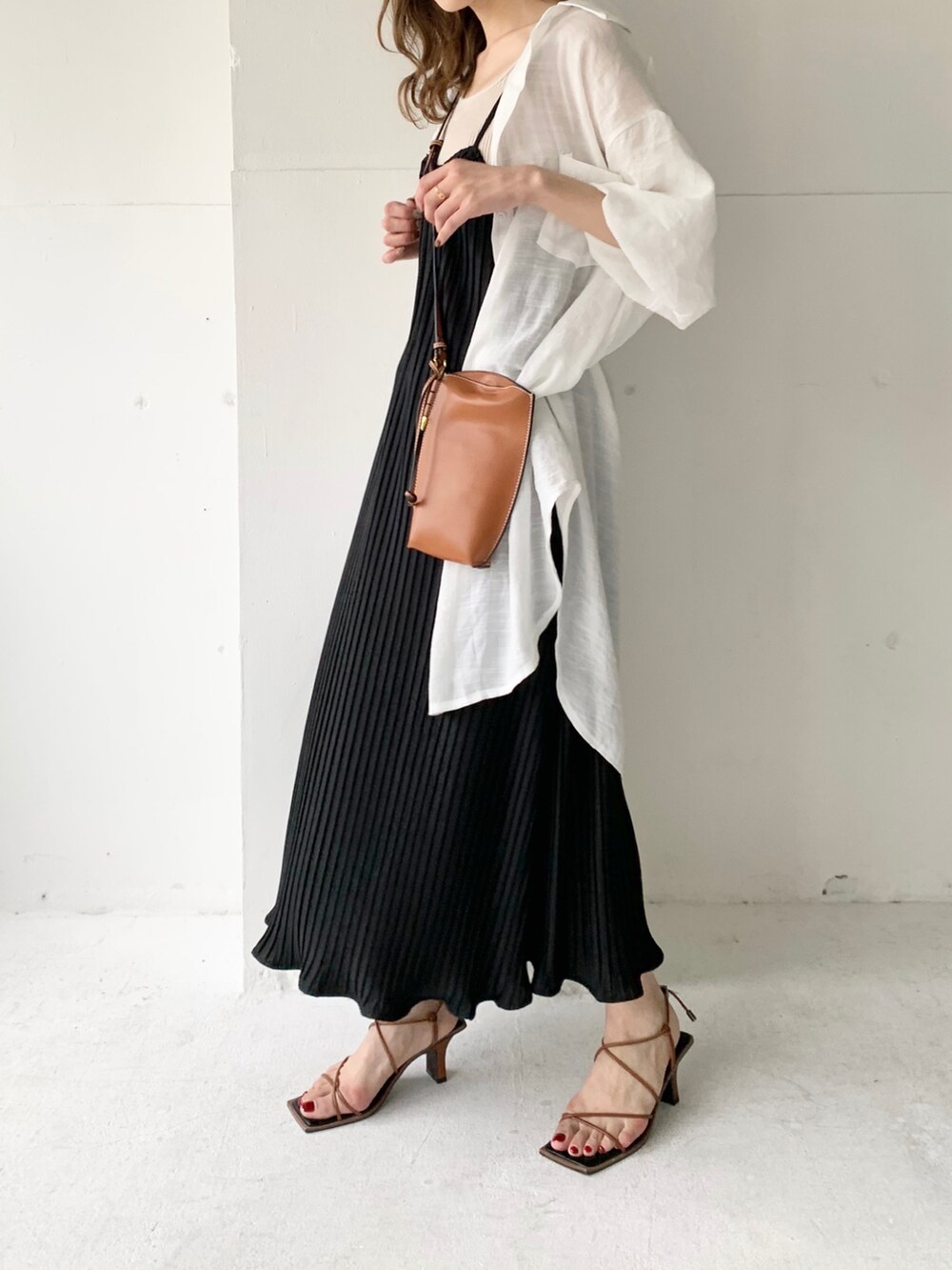 ブラック系のワンピース、ホワイト系のシャツ/ブラウス、ゴールド系のイヤリングを着用したレディースの夏コーディネートの3枚目の写真