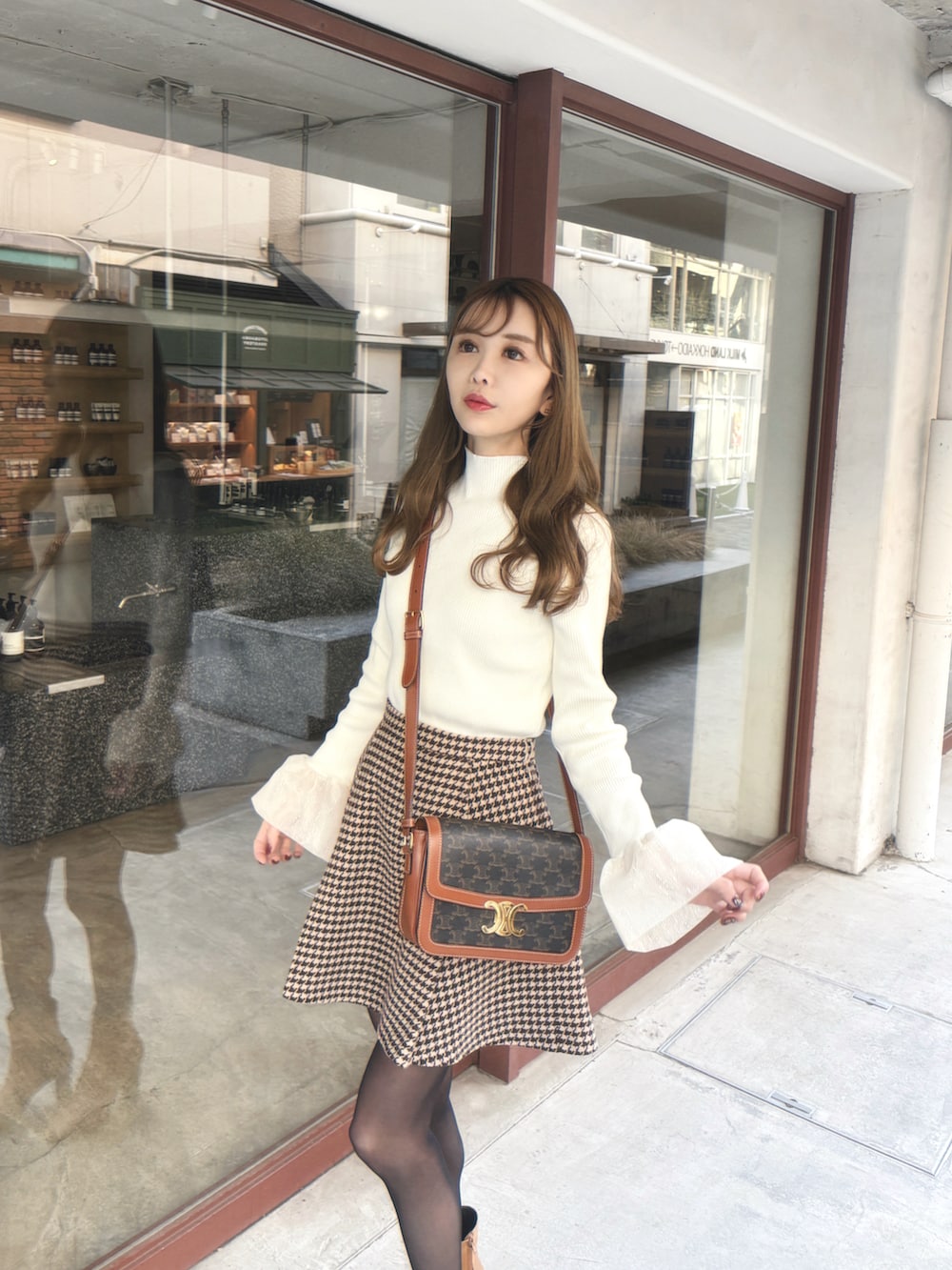 ホワイト系のニット/セーター、ブラウン系のスカートを着用したレディースの冬コーディネートの3枚目の写真