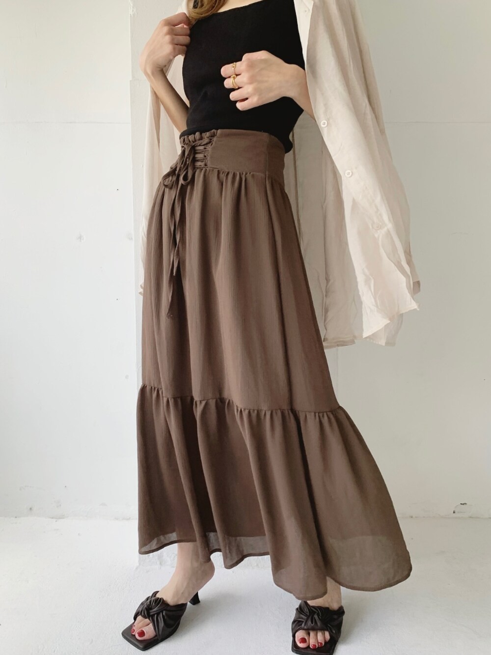 ブラック系のタンクトップ、ブラウン系のスカート、ベージュ系のシャツ/ブラウスを着用したレディースの夏コーディネートの2枚目の写真