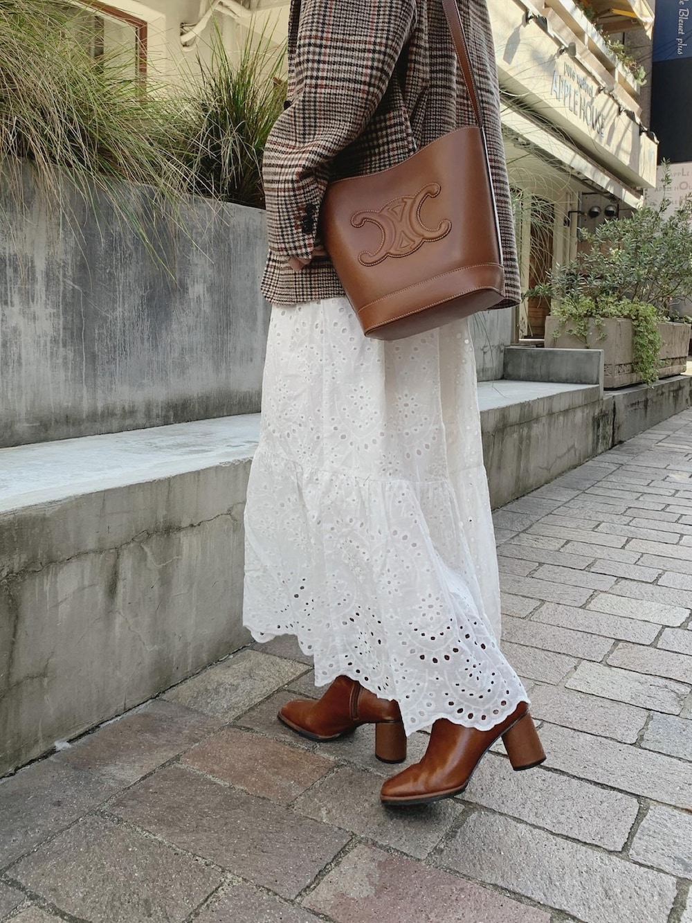 オレンジ系のテーラードジャケット、ホワイト系のニット/セーター、ホワイト系のスカートを着用したレディースの秋コーディネートの4枚目の写真