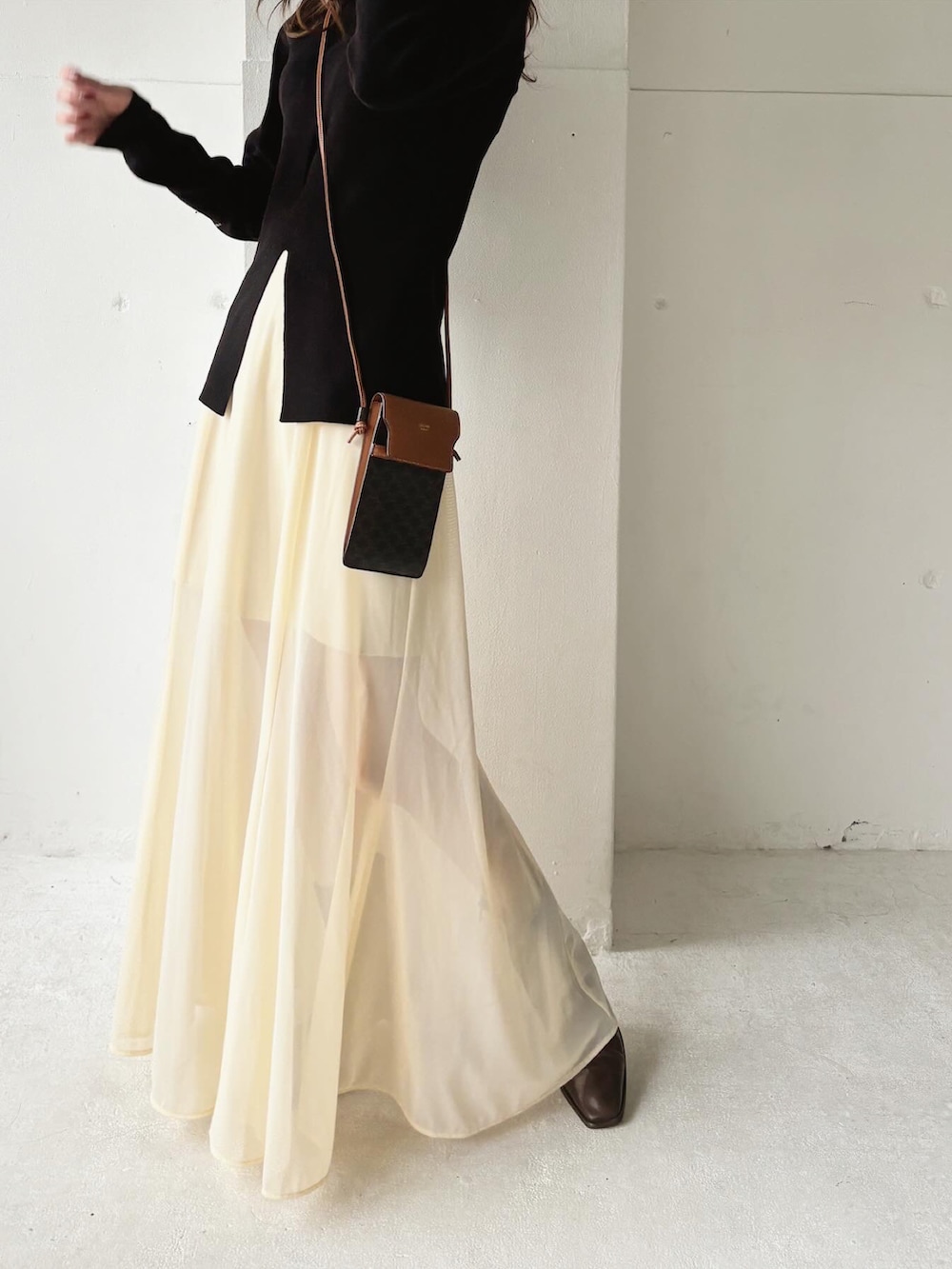 ブラック系のニット/セーター、ホワイト系のスカート、ブラウン系のバッグを着用したレディースの春コーディネートの3枚目の写真