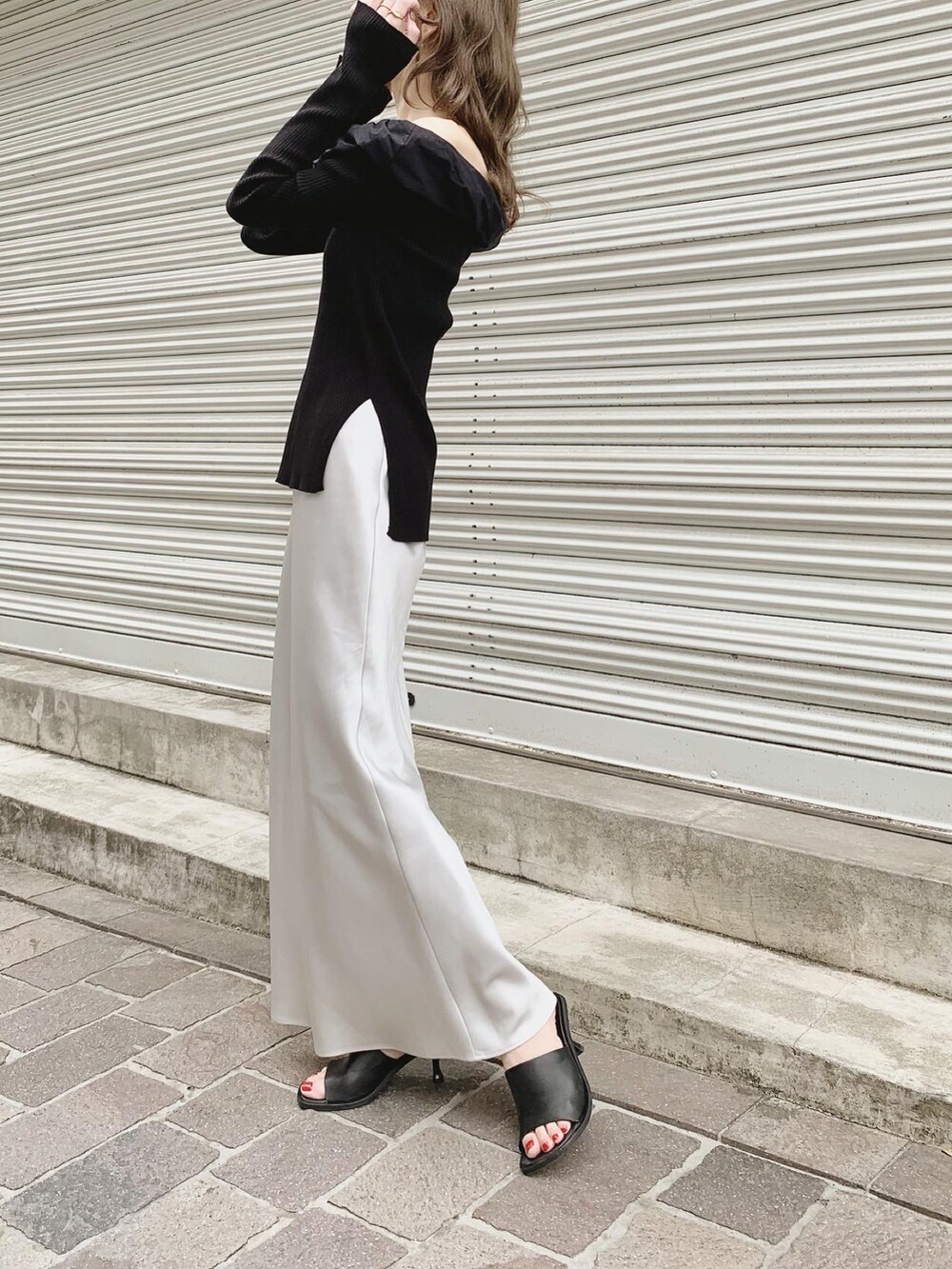 ブラック系のニット/セーター、グレー系のスカート、ブラック系のサンダルを着用したレディースの春コーディネートの5枚目の写真