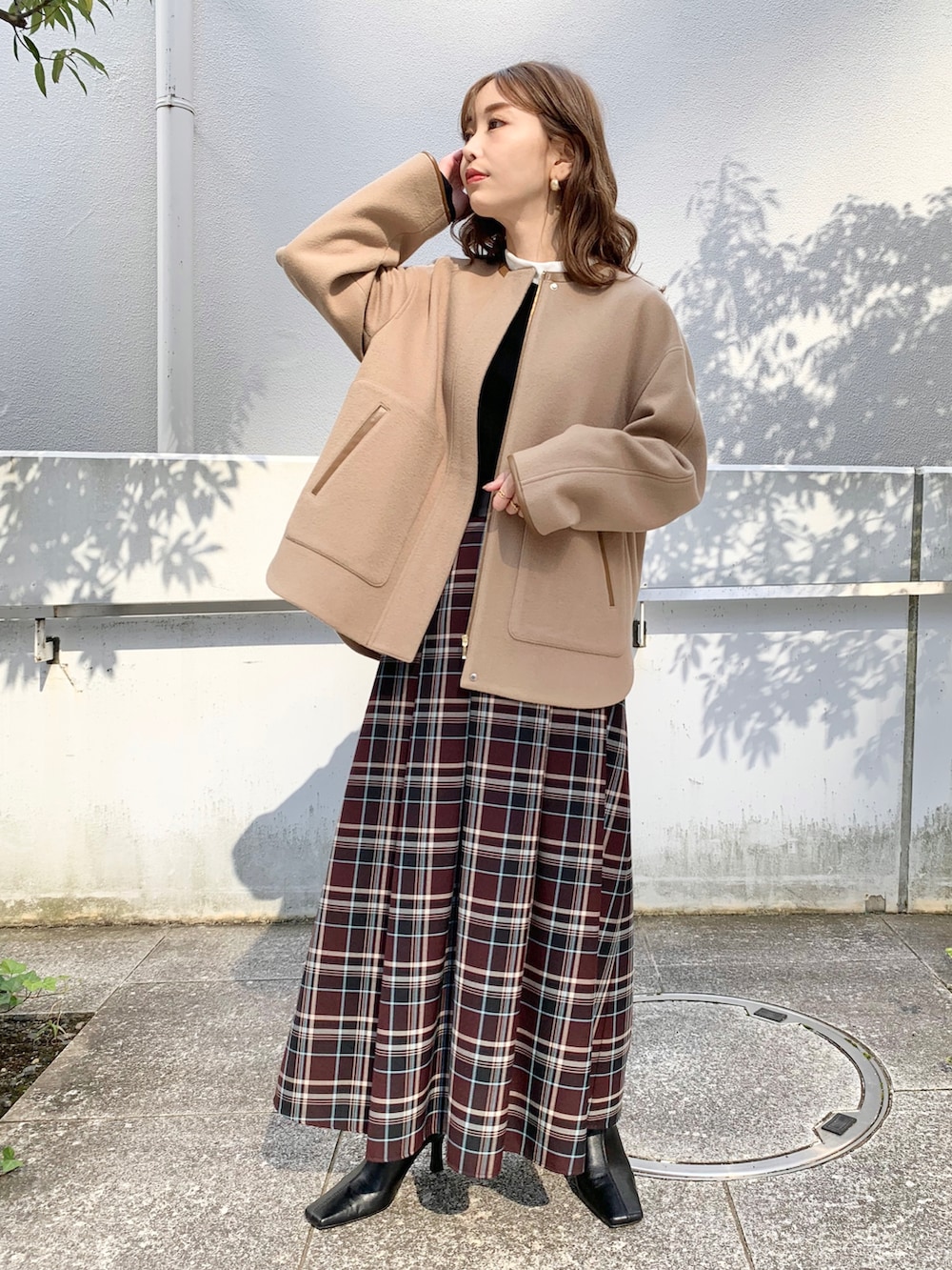 ベージュ系のブルゾン、ブラック系のニット/セーター、レッド系のスカートを着用したレディースの秋コーディネートの2枚目の写真