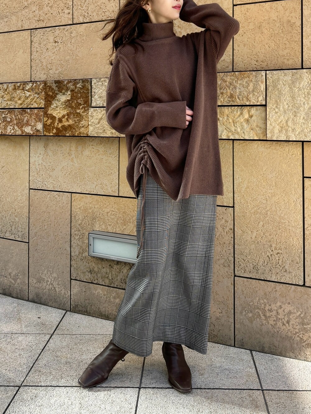 ブラウン系のニット/セーター、ブラック系のスカート、ブラウン系のブーツを着用したレディースの冬コーディネートの4枚目の写真
