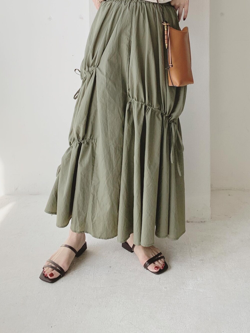 グリーン系のスカート、ブラウン系のサンダル、ホワイト系のTシャツ/カットソーを着用したレディースの夏コーディネートの4枚目の写真