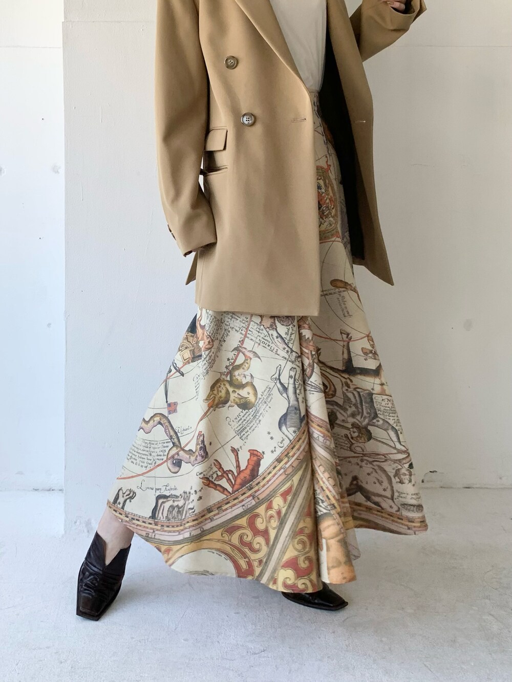 ベージュ系のテーラードジャケット、ホワイト系のニット/セーター、イエロー系のスカートを着用したレディースの春コーディネートの3枚目の写真