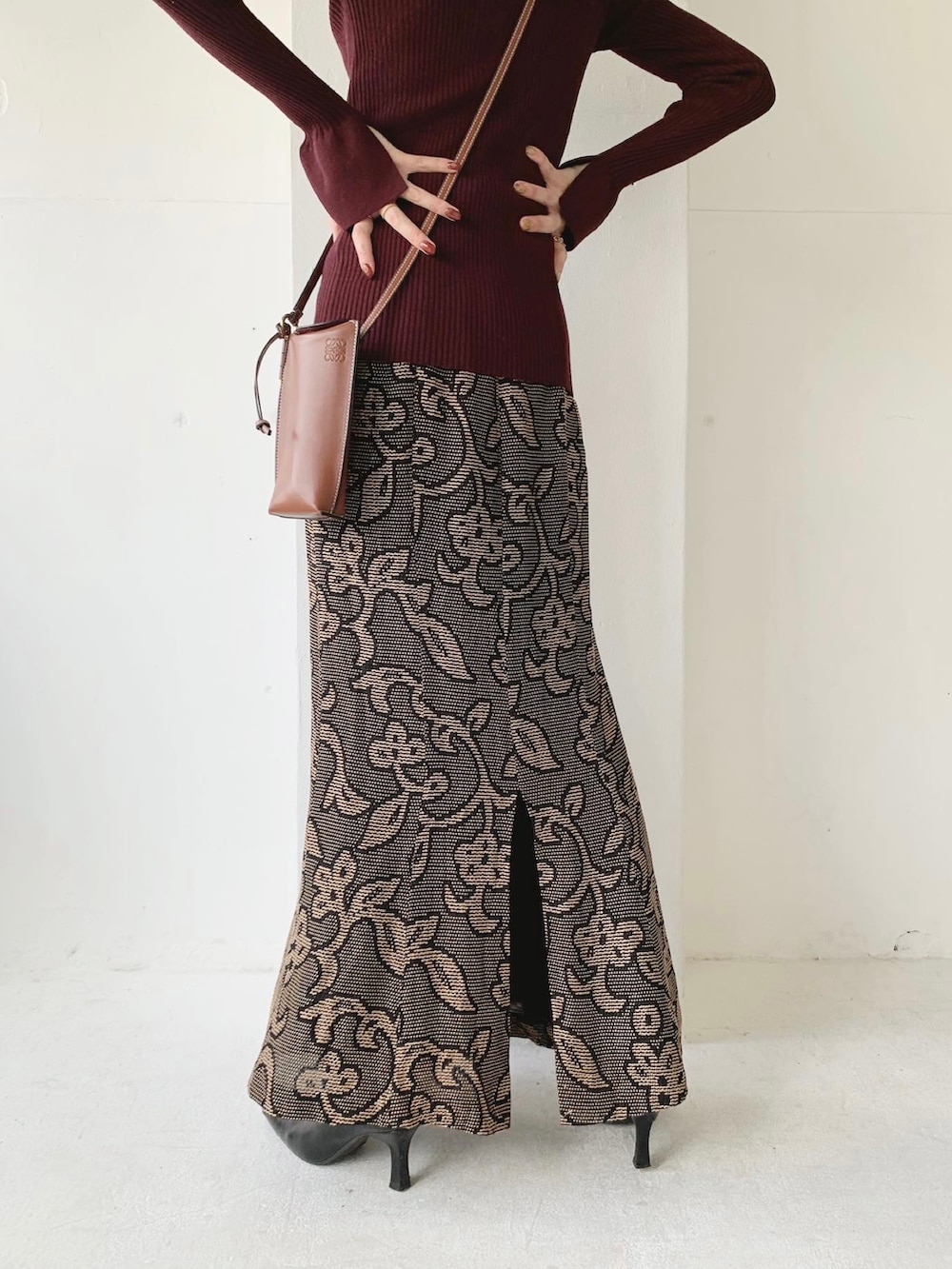 レッド系のニット/セーター、ブラック系のスカート、ブラック系のブーツを着用したレディースの秋コーディネートの4枚目の写真