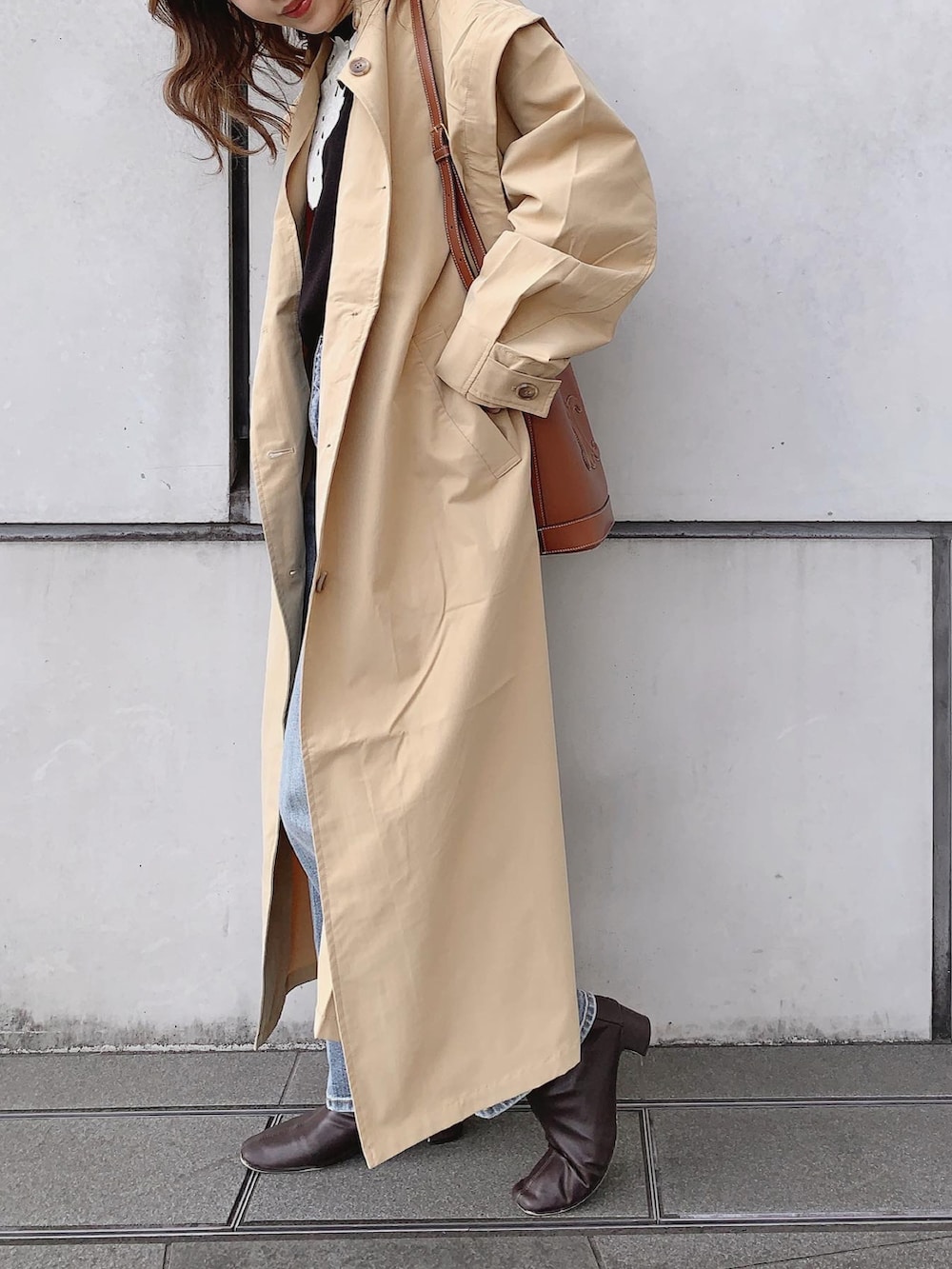 ブルー系のデニムパンツ、ブラウン系のブーツ、ブラック系のニット/セーターを着用したレディースの春コーディネートの3枚目の写真