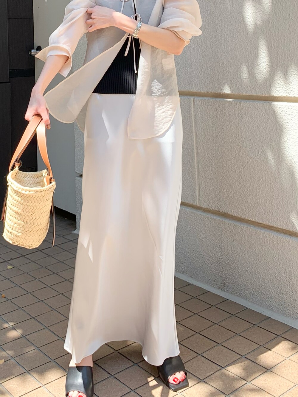 グレー系のスカート、ブラック系のサンダル、ブラック系のチューブトップを着用したレディースの春コーディネートの2枚目の写真