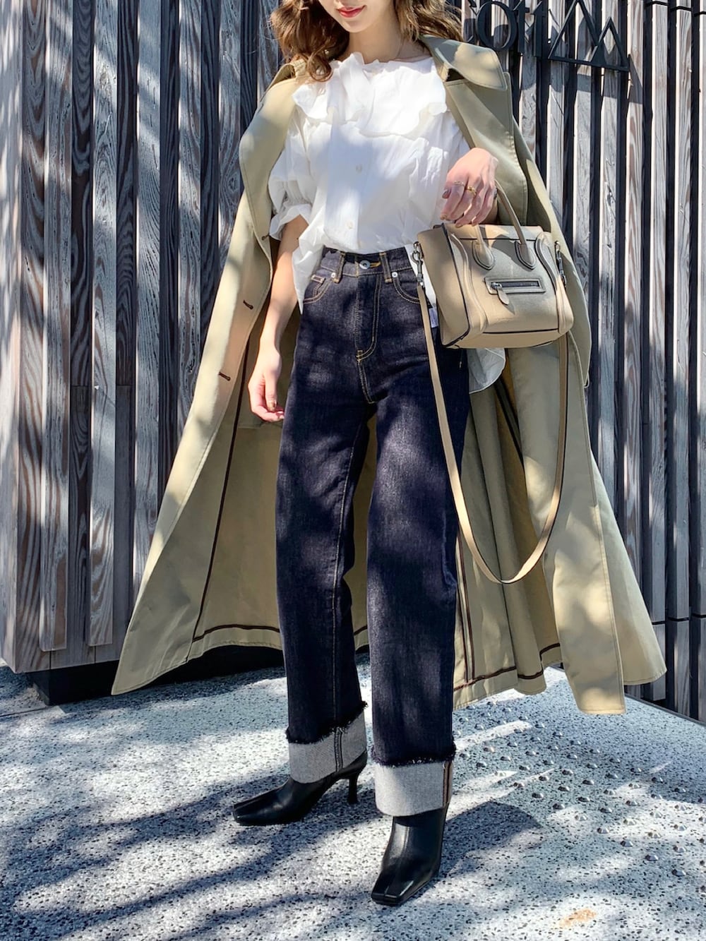 ホワイト系のシャツ/ブラウス、ベージュ系のトレンチコート、ブルー系のデニムパンツを着用したレディースの秋コーディネートの2枚目の写真