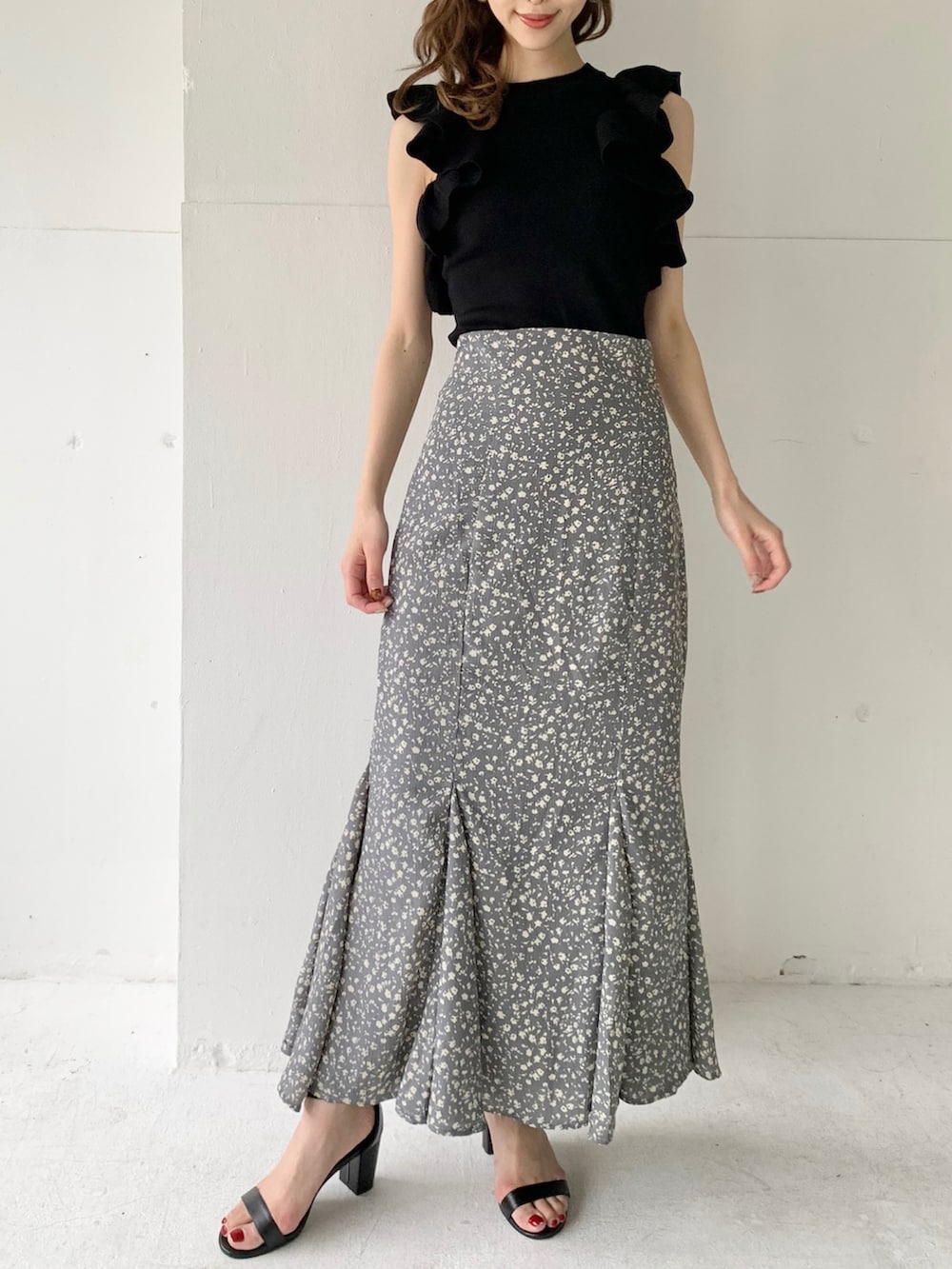 ブルー系のスカート、ブラック系のニット/セーター、ブラック系のサンダルを着用したレディースの夏コーディネートの2枚目の写真