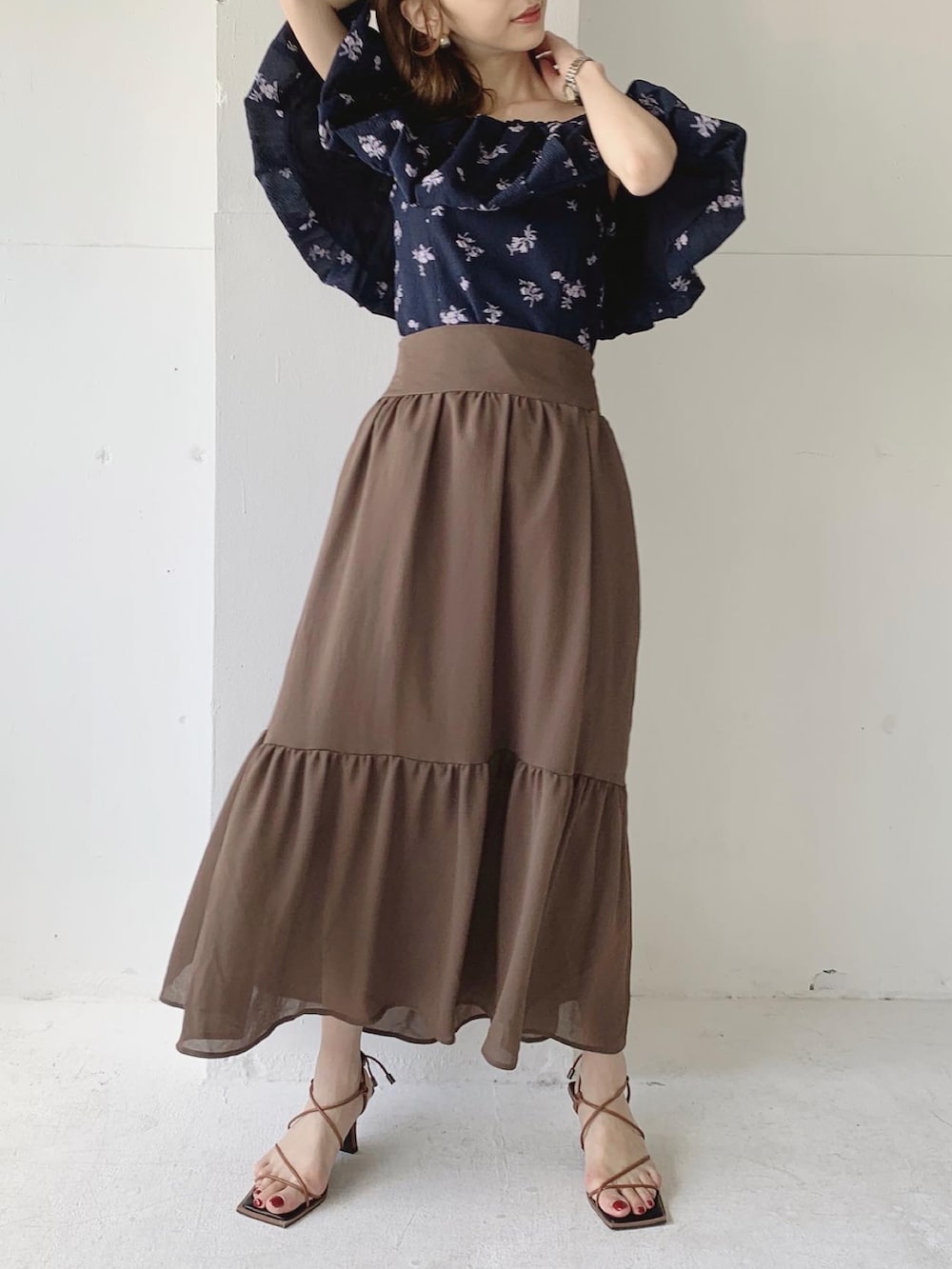 ブラウン系のスカート、ブラウン系のサンダル、ブルー系のシャツ/ブラウスを着用したレディースの夏コーディネートの2枚目の写真