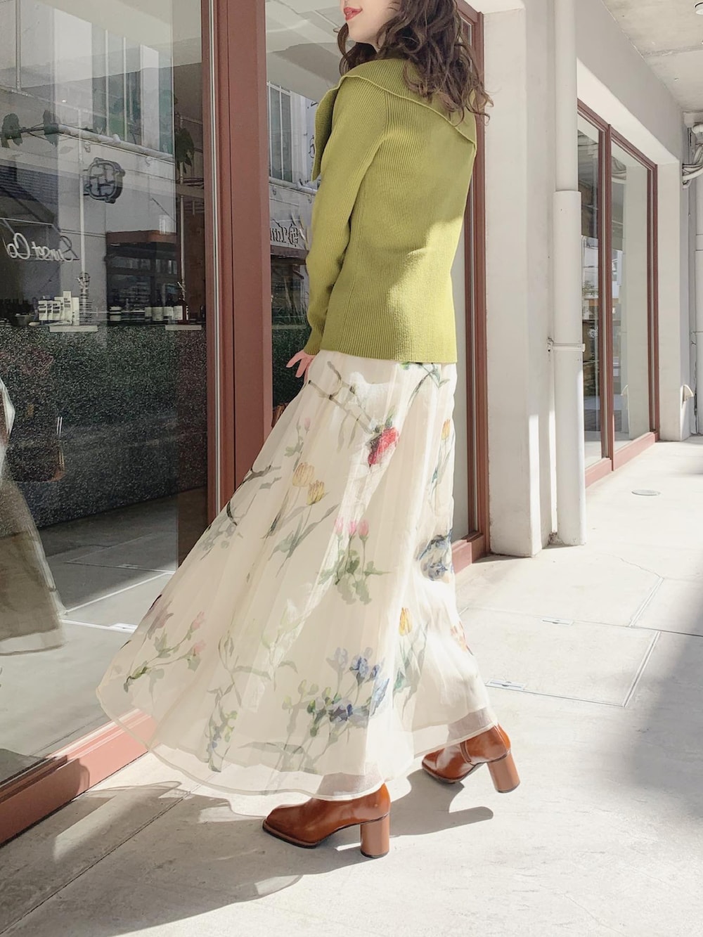 グリーン系のニット/セーター、ホワイト系のスカート、ブラウン系のブーツを着用したレディースの春コーディネートの4枚目の写真