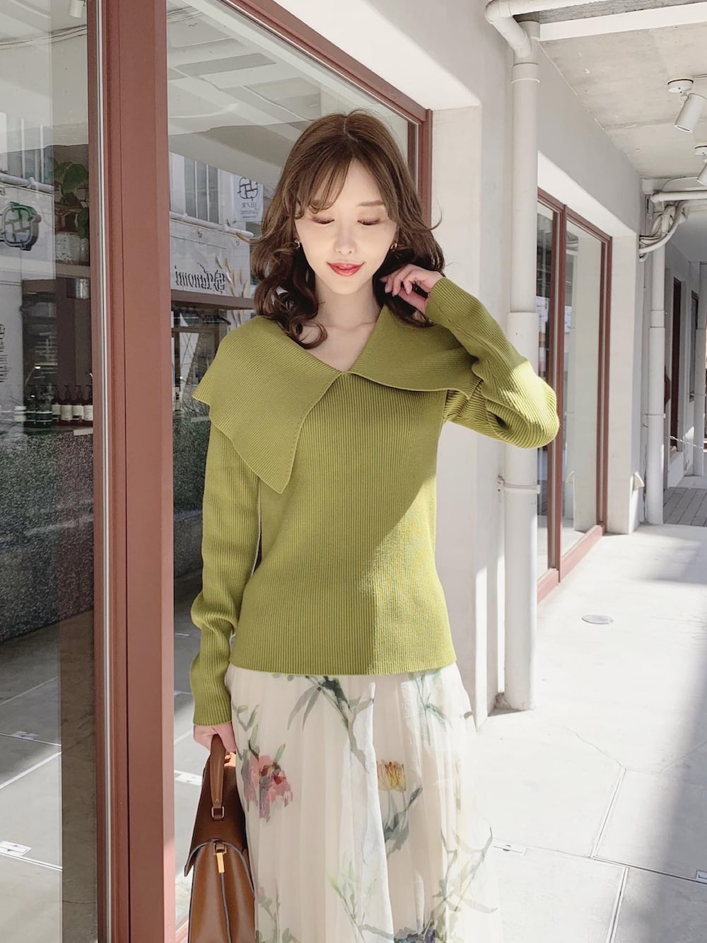 グリーン系のニット/セーター、ホワイト系のスカート、ブラウン系のブーツを着用したレディースの春コーディネートの3枚目の写真