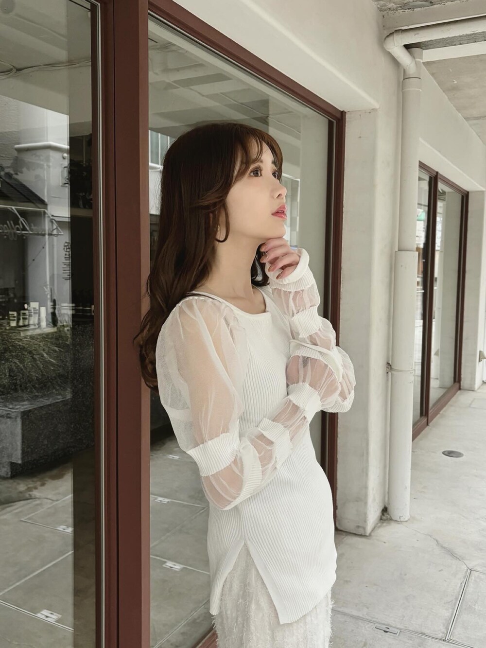 ホワイト系のニット/セーター、ホワイト系のスカート、ブラウン系のブーツを着用したレディースの春コーディネートの2枚目の写真