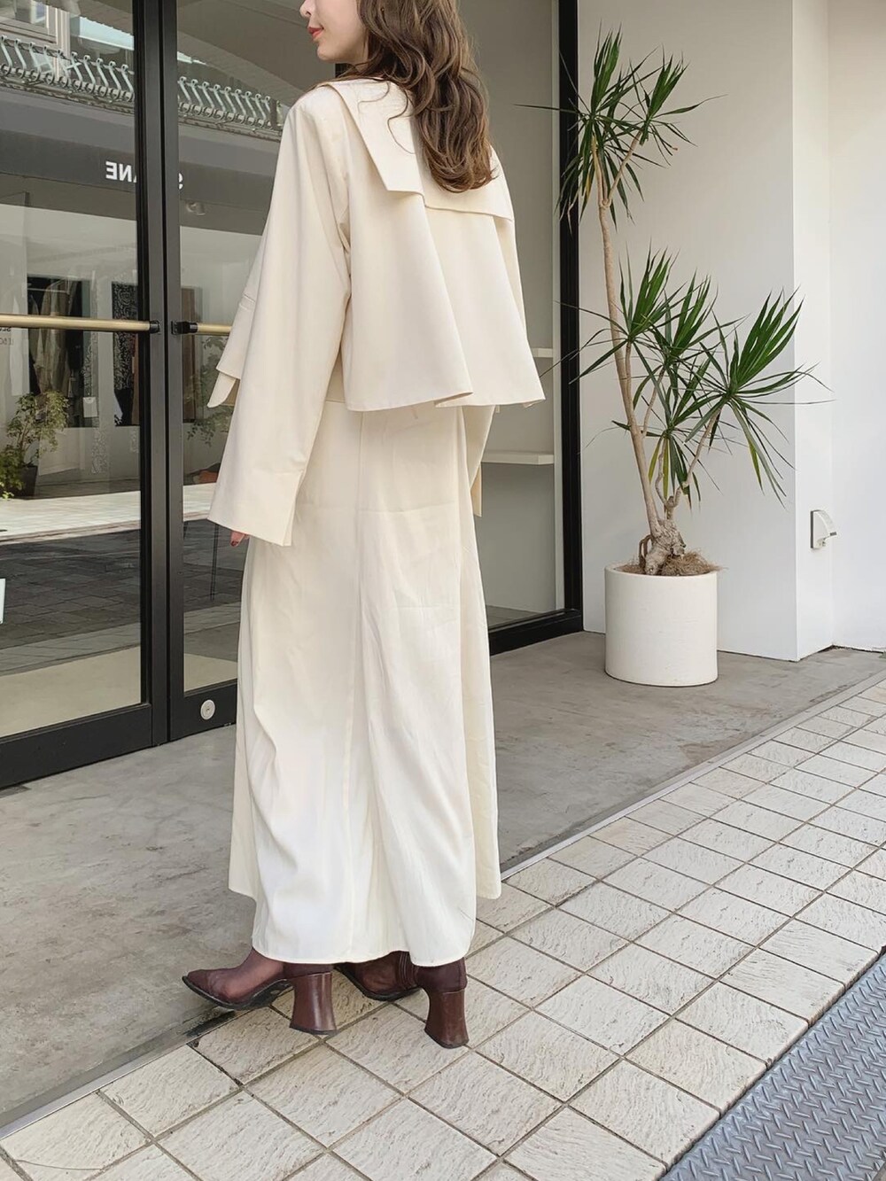 ホワイト系のテーラードジャケット、ホワイト系のワンピース、ブラウン系のブーツを着用したレディースの秋コーディネートの4枚目の写真