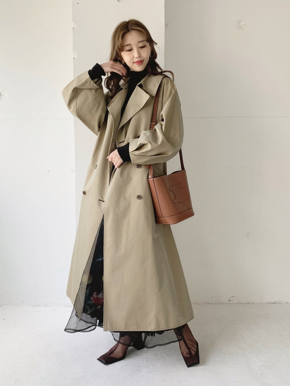 ベージュ系のトレンチコート、ブラック系のスカート、ブラック系のTシャツ/カットソーを着用したレディースの春コーディネートの4枚目の写真